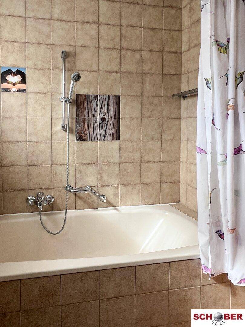 Badewanne mit Duschvorhang und Fliesen an den Wänden, funktional und sauber.