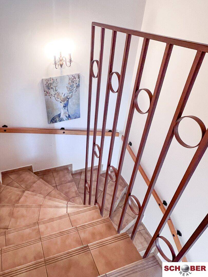 Geflieste Treppe mit dekorativem Metallgeländer, die die verschiedenen Etagen verbindet.