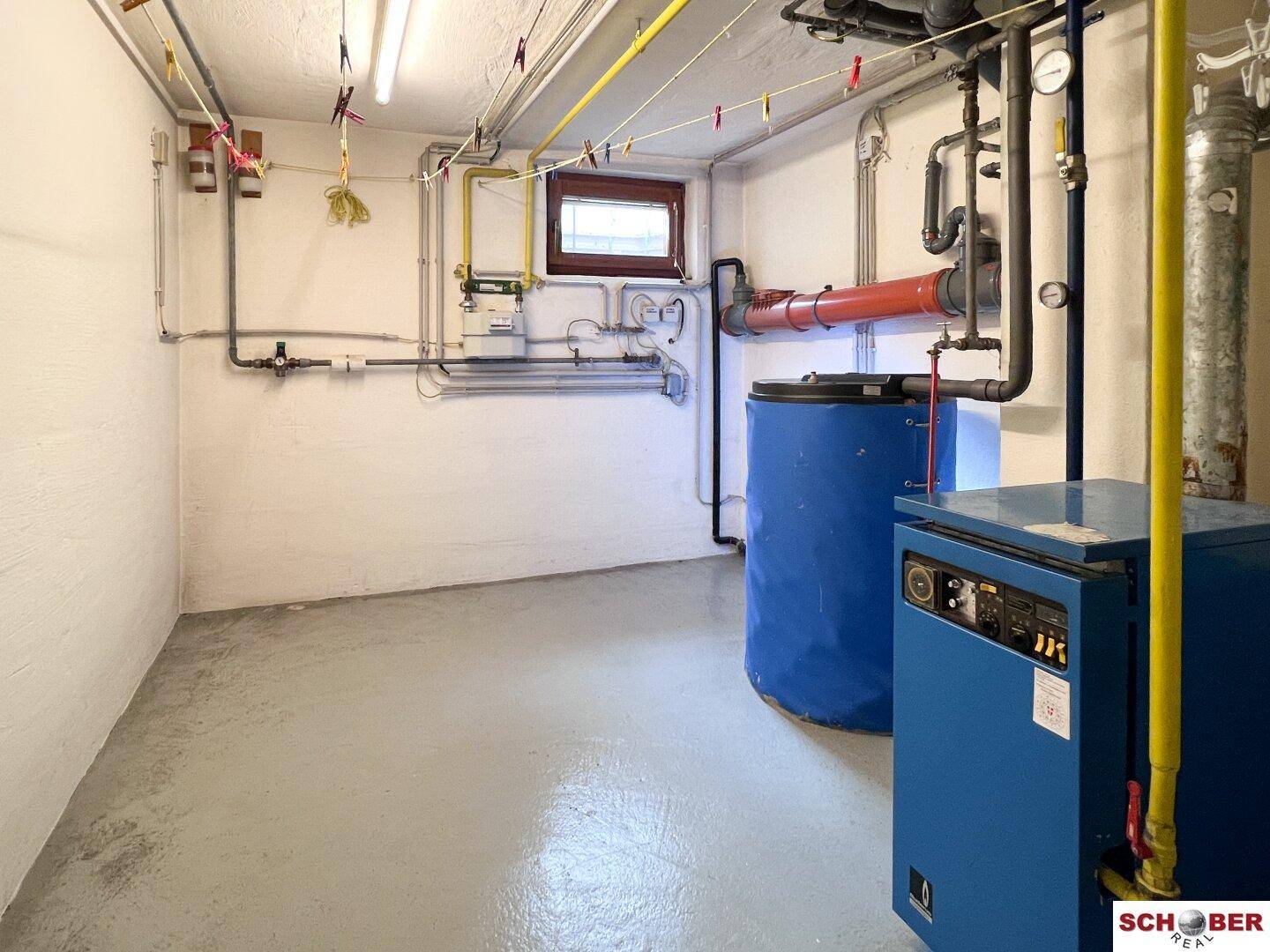 Heizungsraum im Keller mit Boiler, Rohren und technischen Installationen.