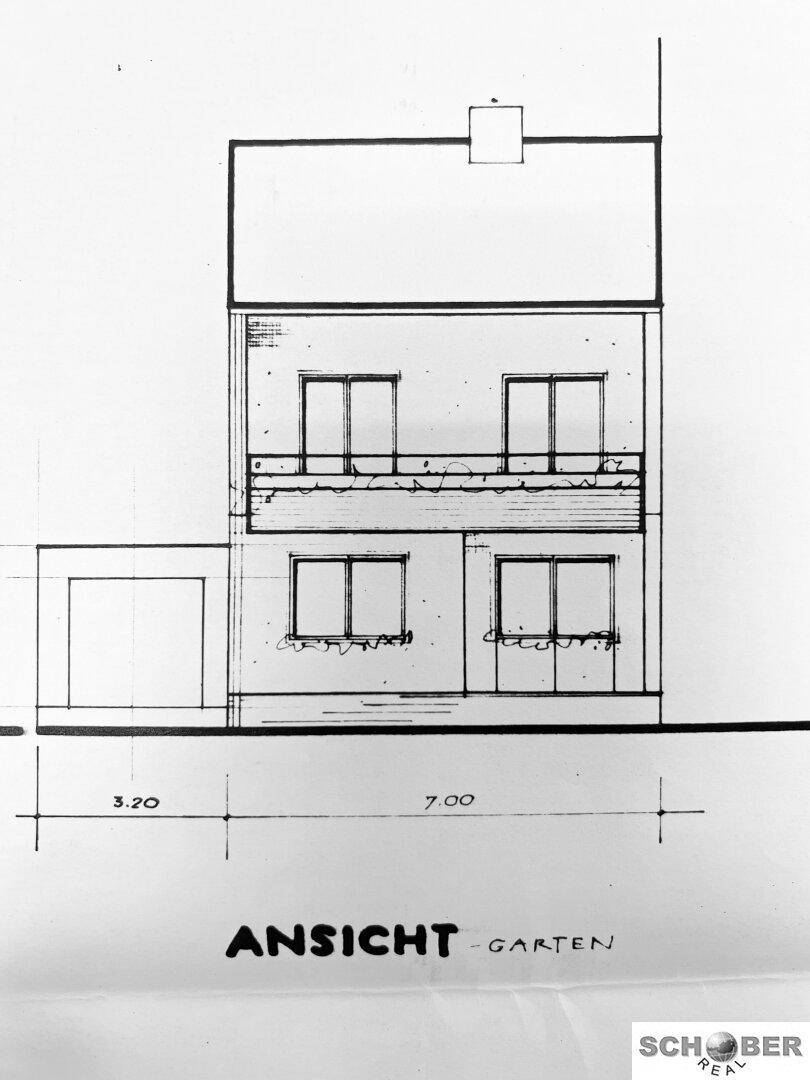 Ansicht des Gebäudes von der Gartenseite mit Fenstern und Balkon.