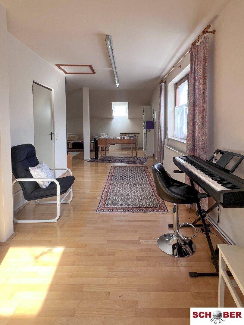 Geräumiges Dachzimmer mit Holzboden, viel Tageslicht und Blick in den hinteren Bereich.