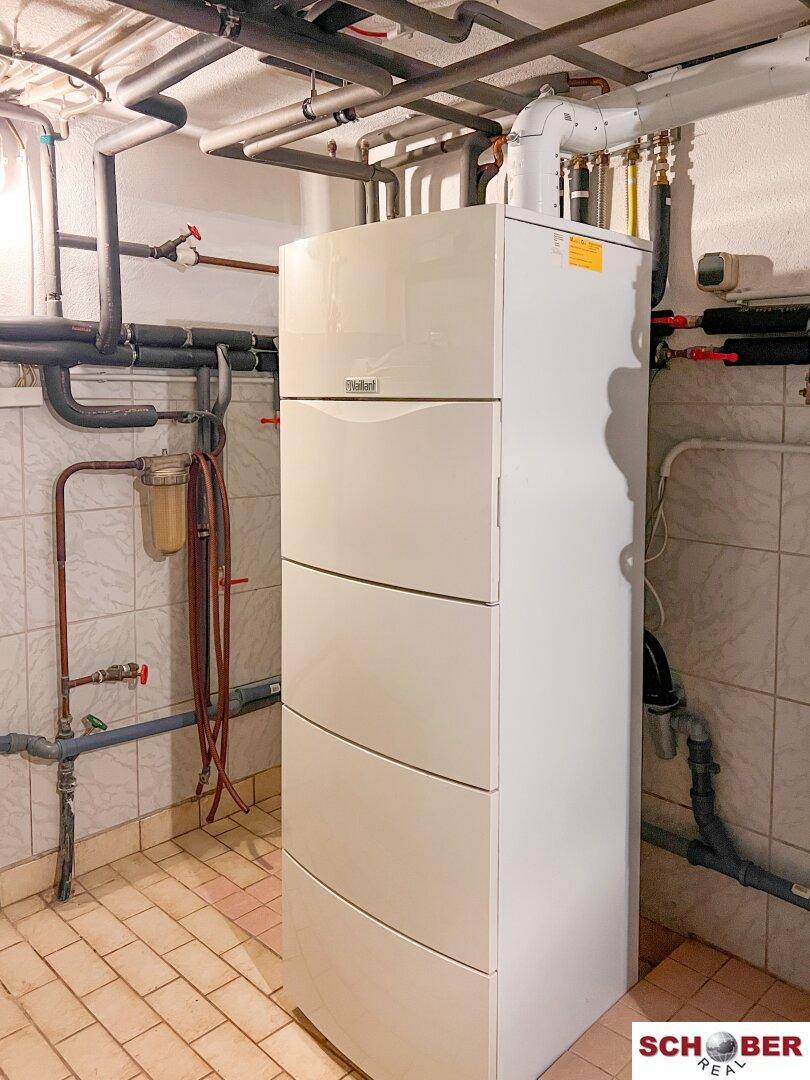 Heizungsraum im Keller mit moderner Heizungsanlage und sichtbaren Rohren, gut organisiert und sauber.