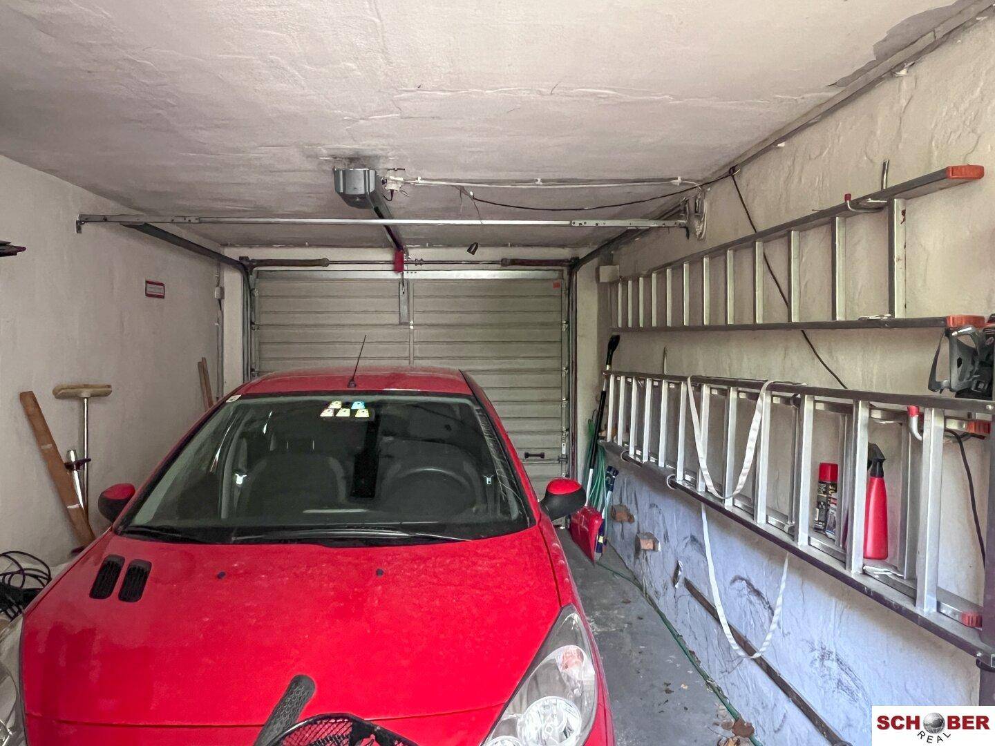 Geräumige Garage mit Rolltor und Platz für ein Fahrzeug, inklusive Lagerfläche.