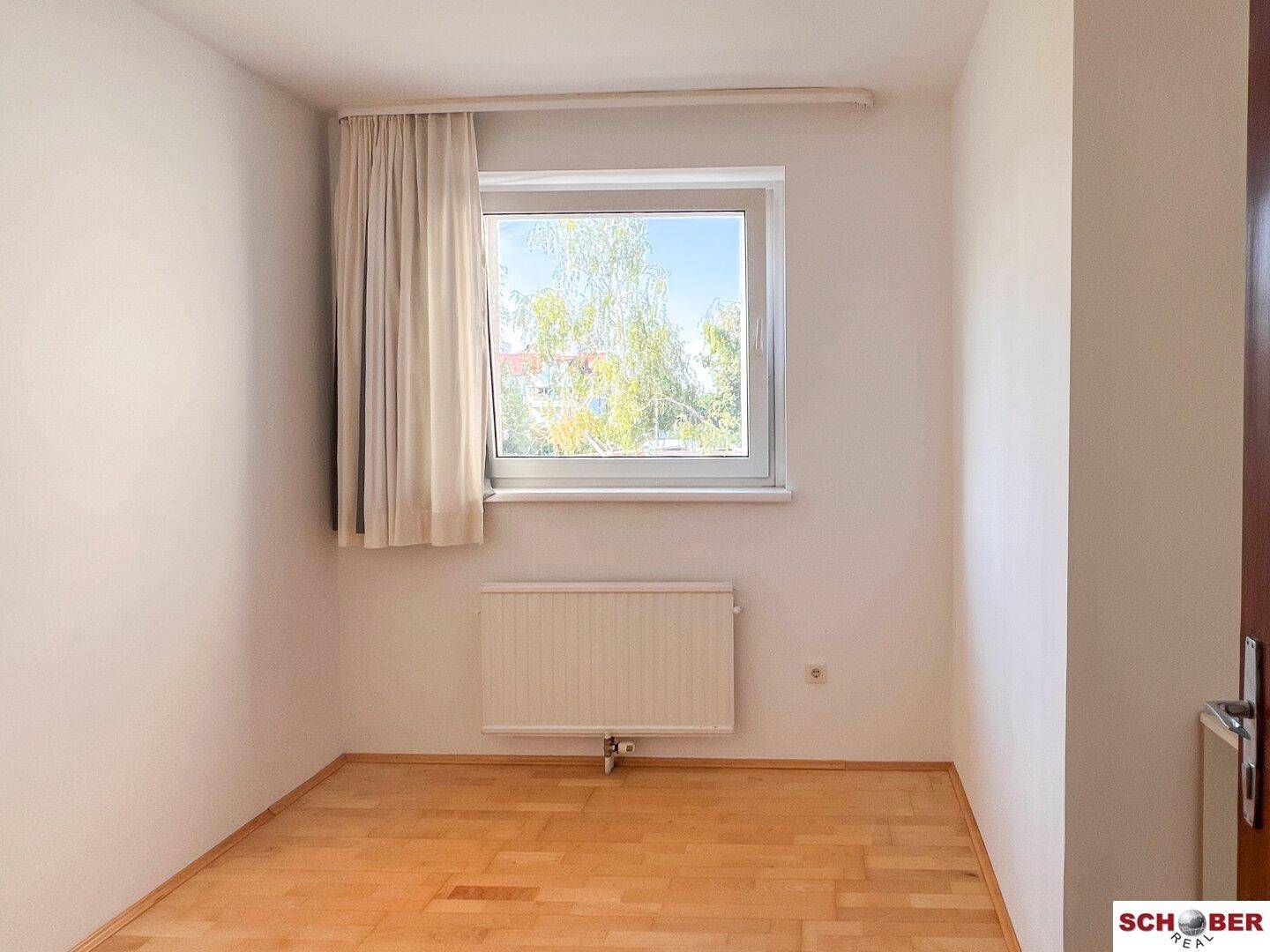 Freundliches Zimmer mit Parkettboden und Fenster, gut belichtet.
