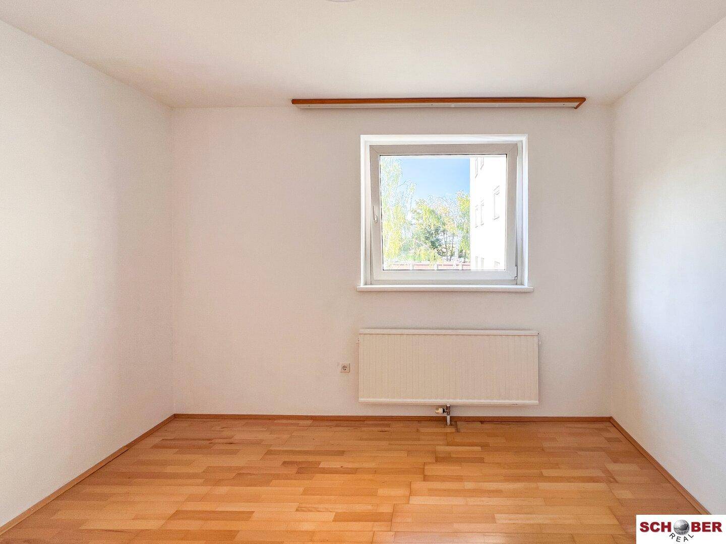 Helles Zimmer mit Parkettboden und Fenster, ideal als Schlaf- oder Arbeitszimmer.