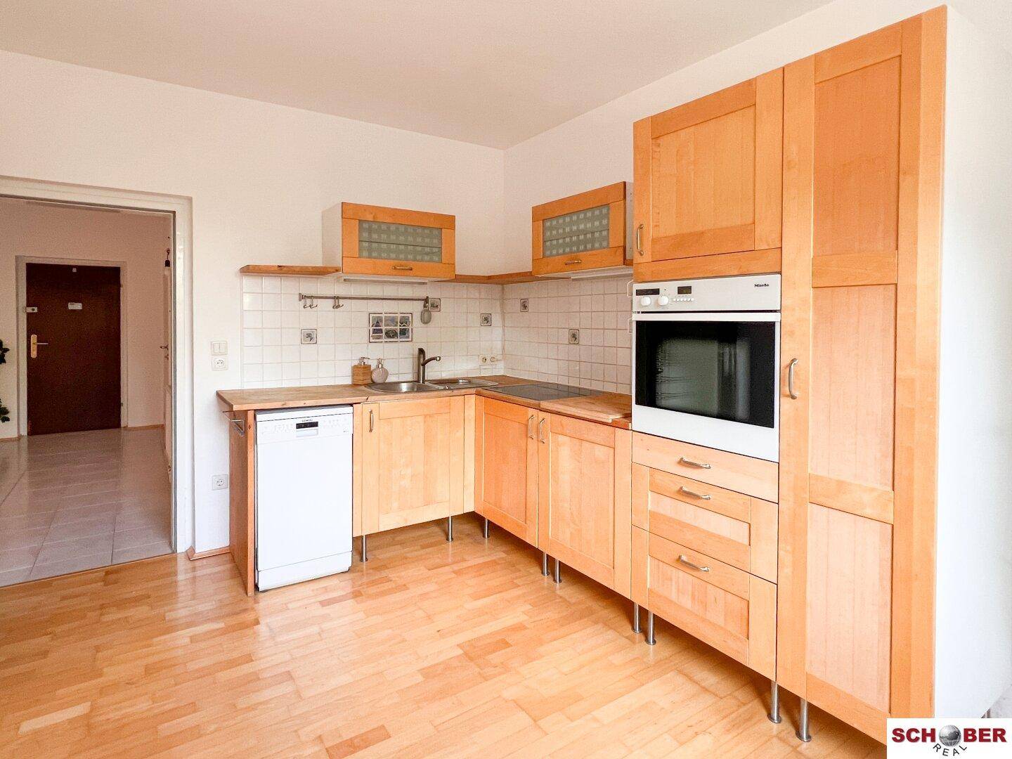 Helle Einbauküche mit Holzfronten, Spülmaschine und ausreichend Arbeitsfläche.