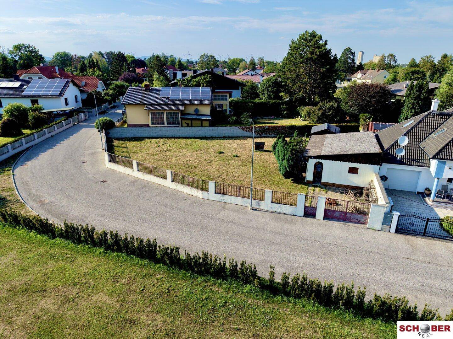 Ansicht des Grundstücks von der Straße, mit dem Haus, großem Rasen und Solaranlagen auf dem Dach.