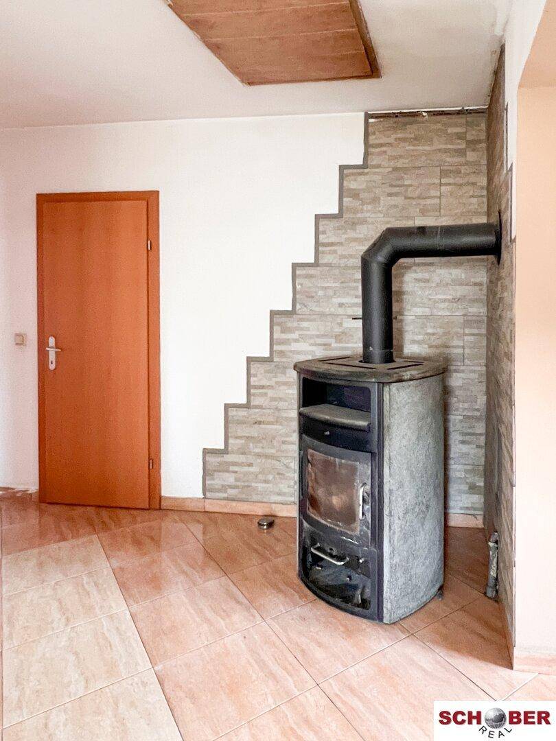 Gemütlicher Raum mit Fliesenboden und einem Holzofen, der Wärme spendet und Atmosphäre schafft.