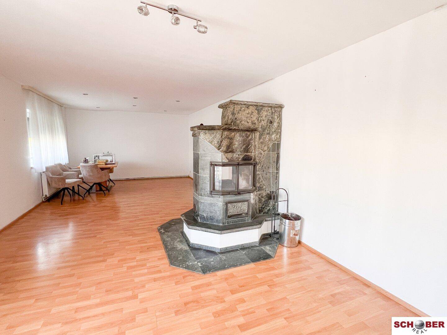 Großes Wohnzimmer mit Holzboden und einem traditionellen Kamin, der Gemütlichkeit schafft.