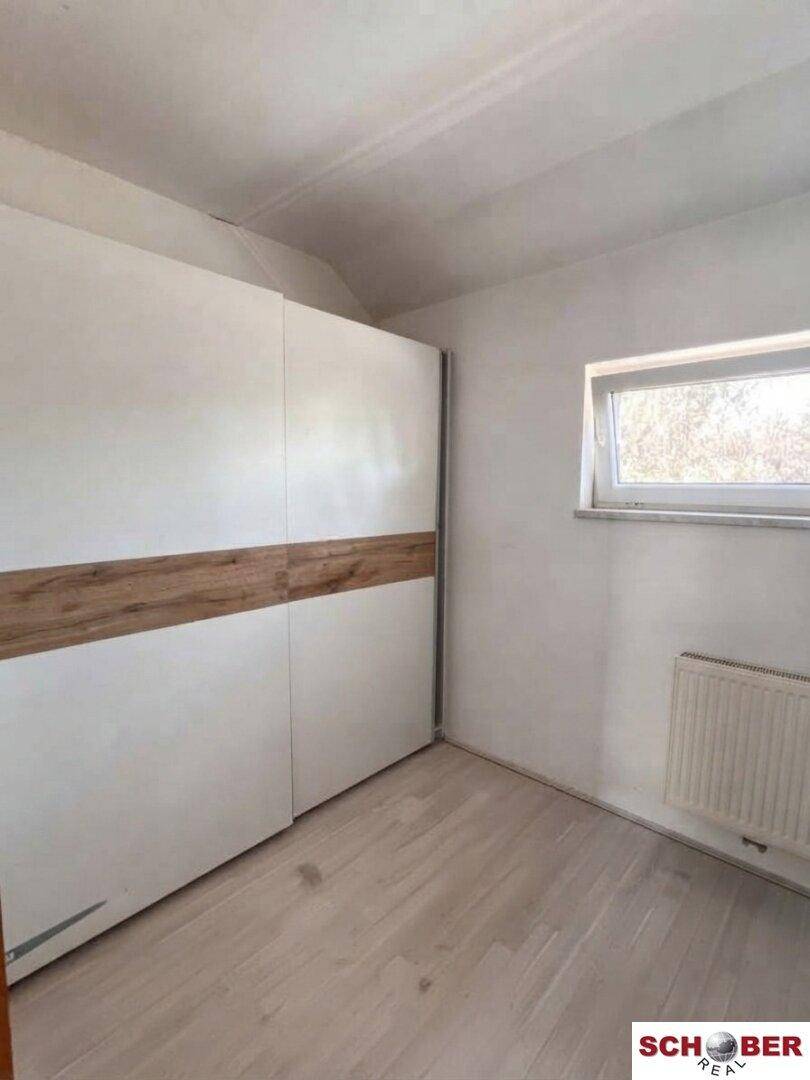 Schlafzimmer mit Laminatboden und einem großen Einbauschrank, der viel Stauraum bietet.