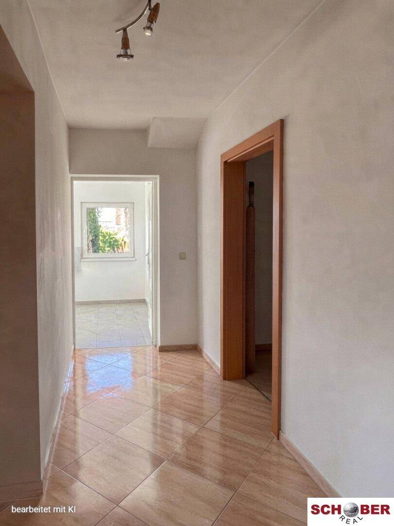 Heller Flur mit glänzenden Fliesen und Holztüren, der zu weiteren Räumen führt.