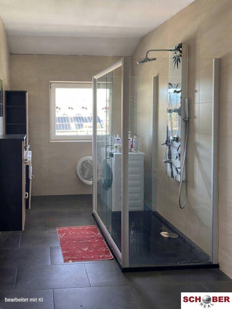 Modernes Badezimmer mit großer Duschkabine, dunklen Bodenfliesen und einem Fenster.