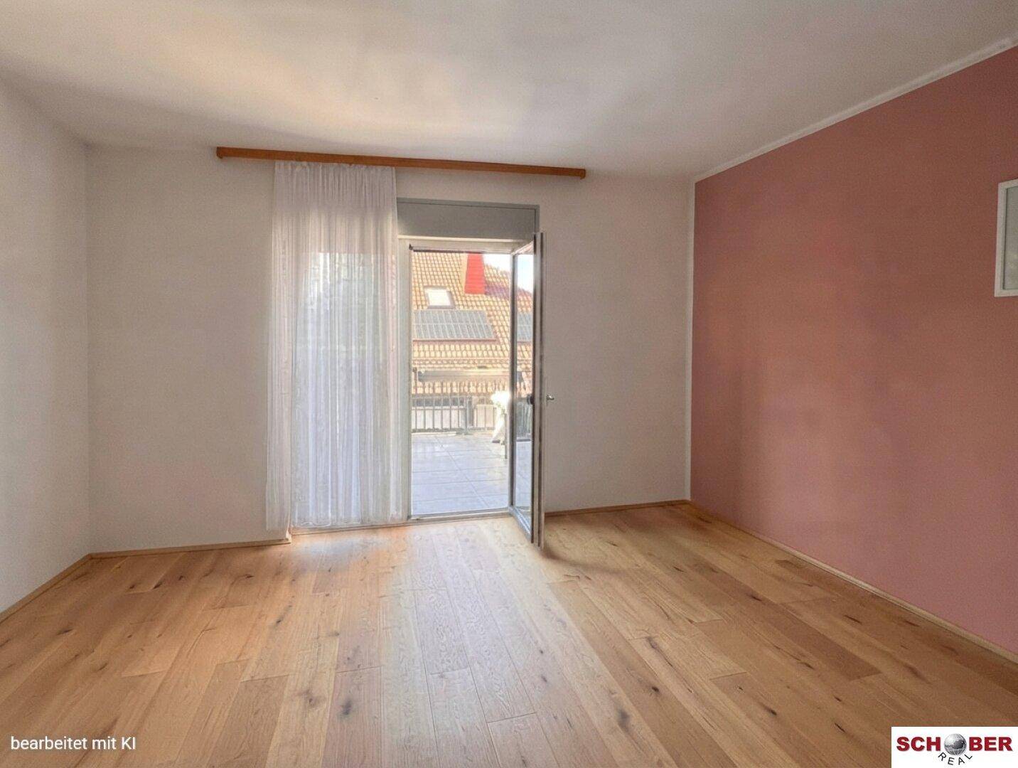 Geräumiges Schlafzimmer mit Holzboden, rosa Akzentwand und direktem Zugang zum Balkon.