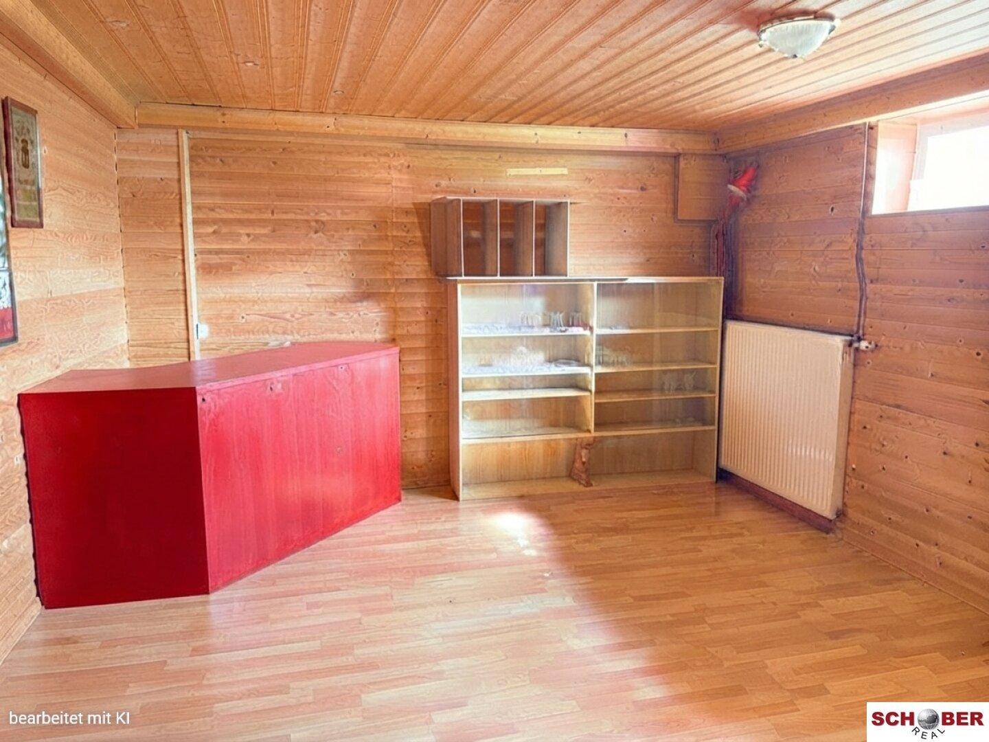 Rustikaler Raum im Untergeschoss mit Holzverkleidung, Laminatboden und Regalen.