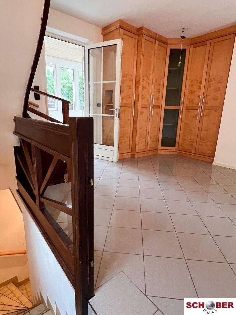 Flur mit Fliesenboden und Einbauschränken aus Holz, führt zu einer Außentür.