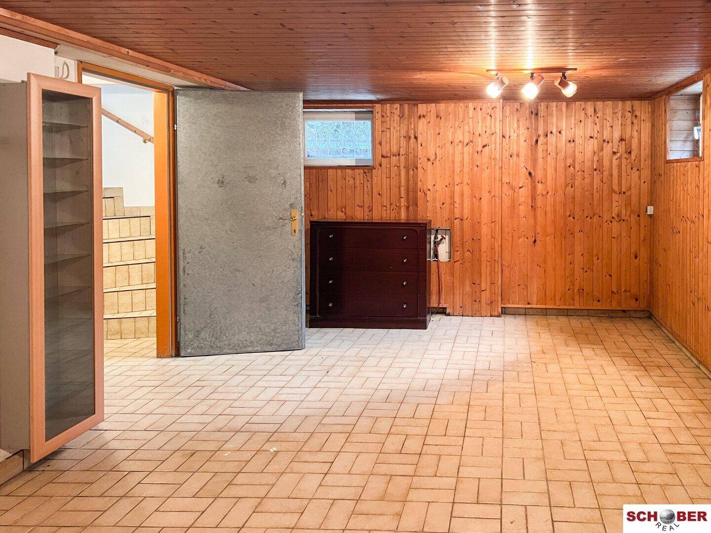 Ausgebauter Kellerraum mit Holzvertäfelung, Fliesenboden und einem kleinen Fenster.