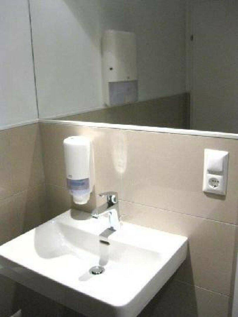 Modernes Waschbecken mit Seifenspender und Spiegel in einem gepflegten Badezimmer.
