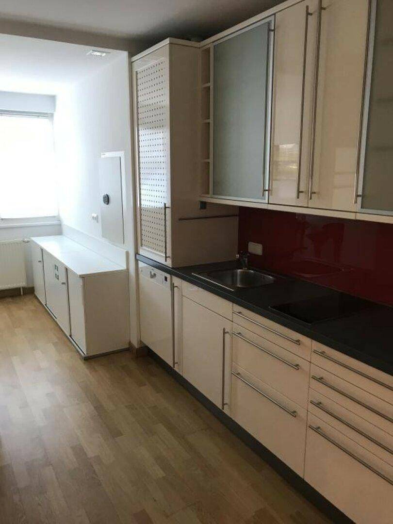 Moderne Küchenzeile mit weißen Schränken, dunkler Arbeitsplatte, Spüle und Induktionskochfeld.