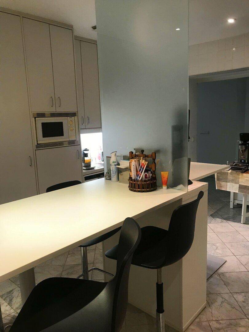 Moderne Küchenzeile mit integrierter Mikrowelle und einer Bar mit Hockern.