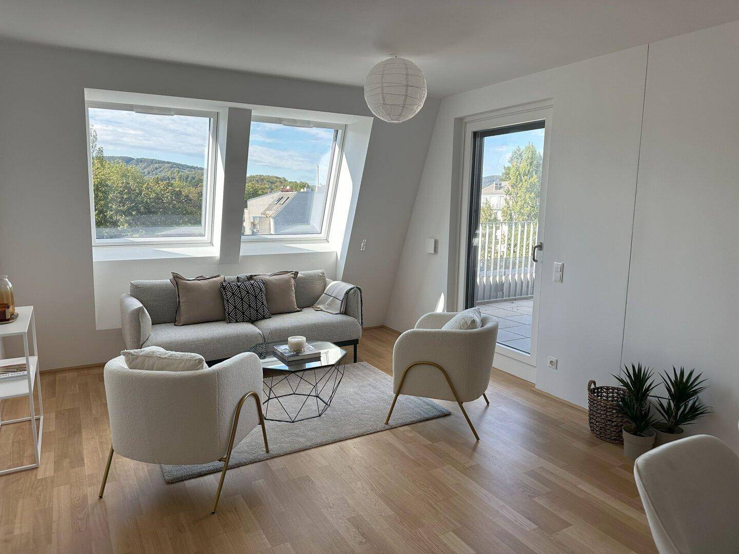 Helles Wohnzimmer mit Dachschrägen, Holzboden und Zugang zu einer Terrasse.