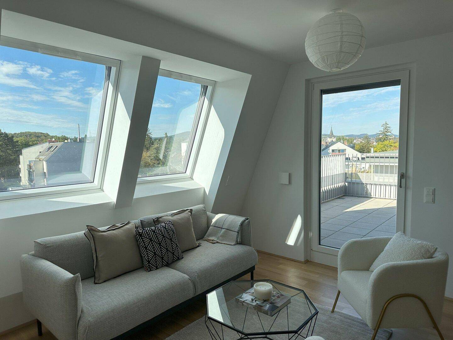 Gemütliches Wohnzimmer mit Dachfenstern, Holzboden und Blick auf die Umgebung.