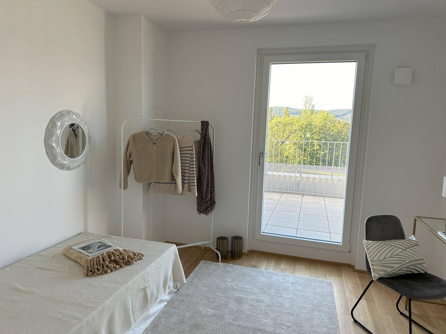 Schlafzimmer mit Holzboden, Zugang zur Terrasse und minimalistischer Einrichtung.