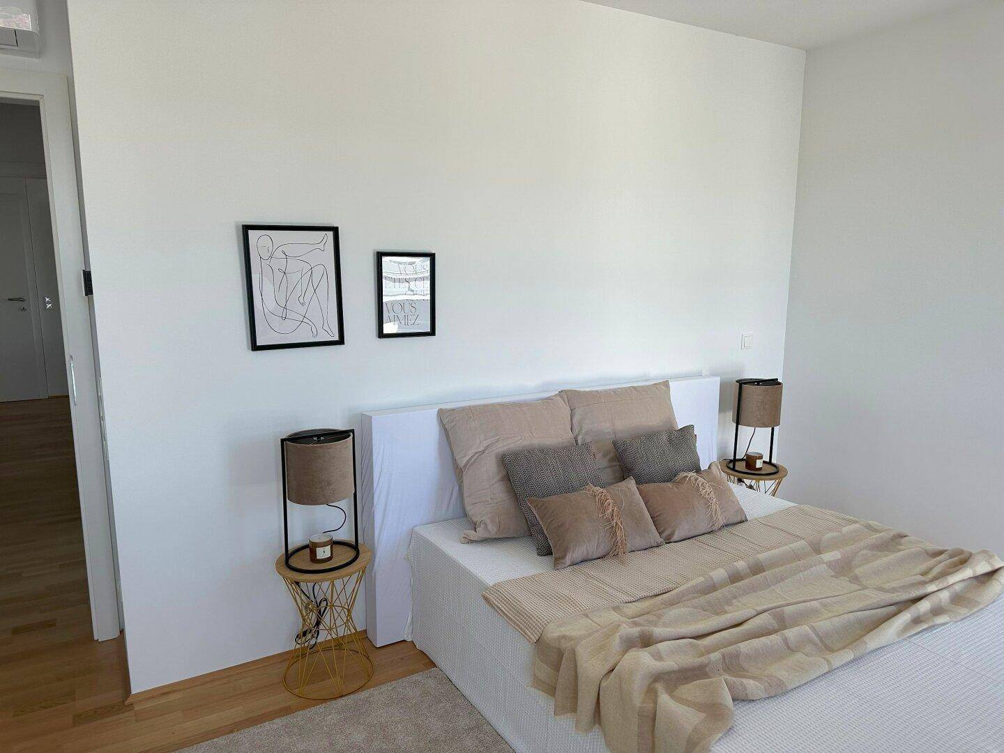 Schlafzimmer mit Doppelbett, Holzboden und schlichter, moderner Dekoration.