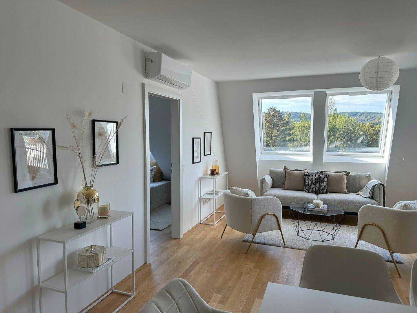 Modern eingerichtetes Wohnzimmer mit Dachschrägen, Holzboden und Klimaanlage.