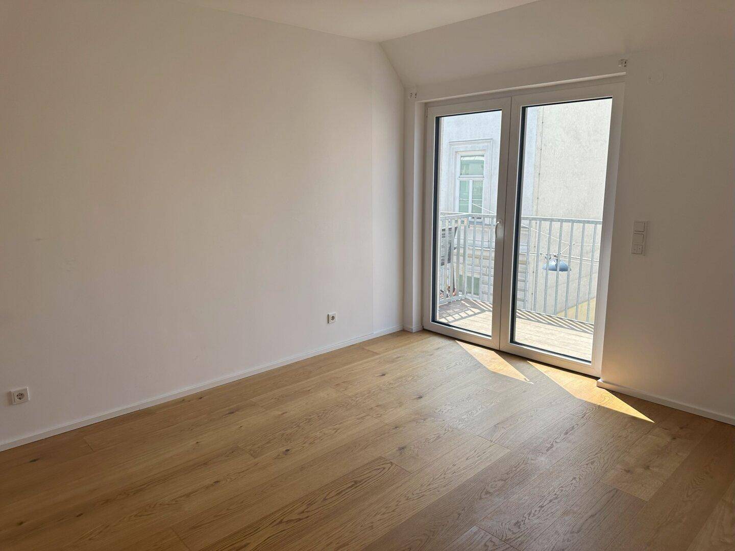 Helles Zimmer mit Parkettboden und Zugang zu einem französischen Balkon, ideal als Schlafzimmer.