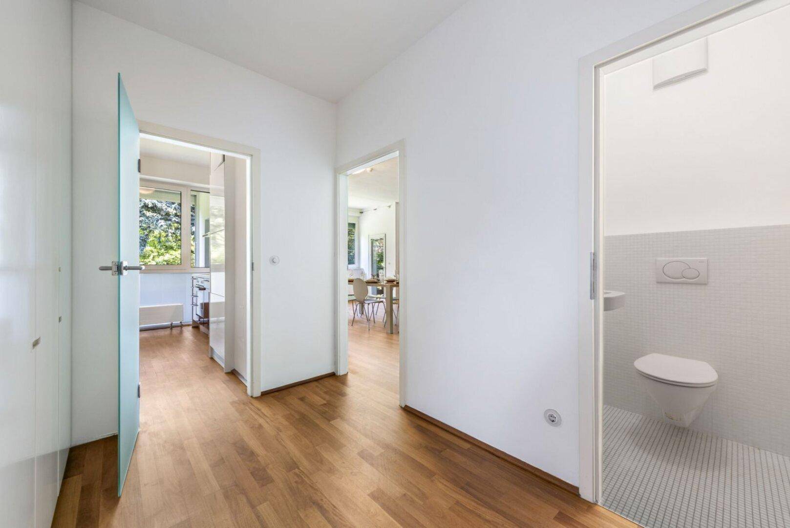 Heller Flur mit Parkettboden und Zugang zu verschiedenen Räumen, inklusive dem Gäste-WC.