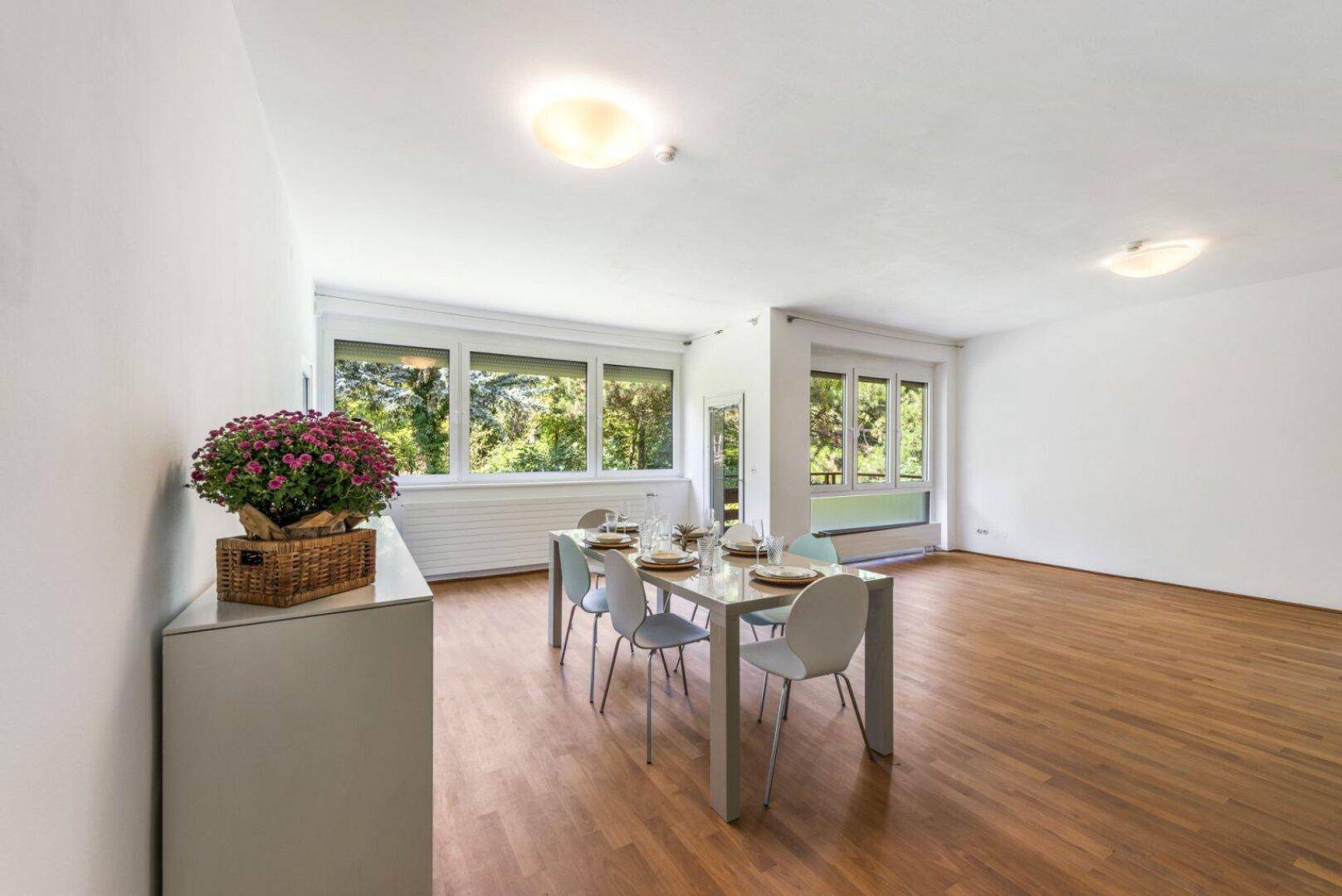 Geräumiger Essbereich mit gedecktem Tisch und großen Fenstern, die viel Tageslicht hereinlassen.