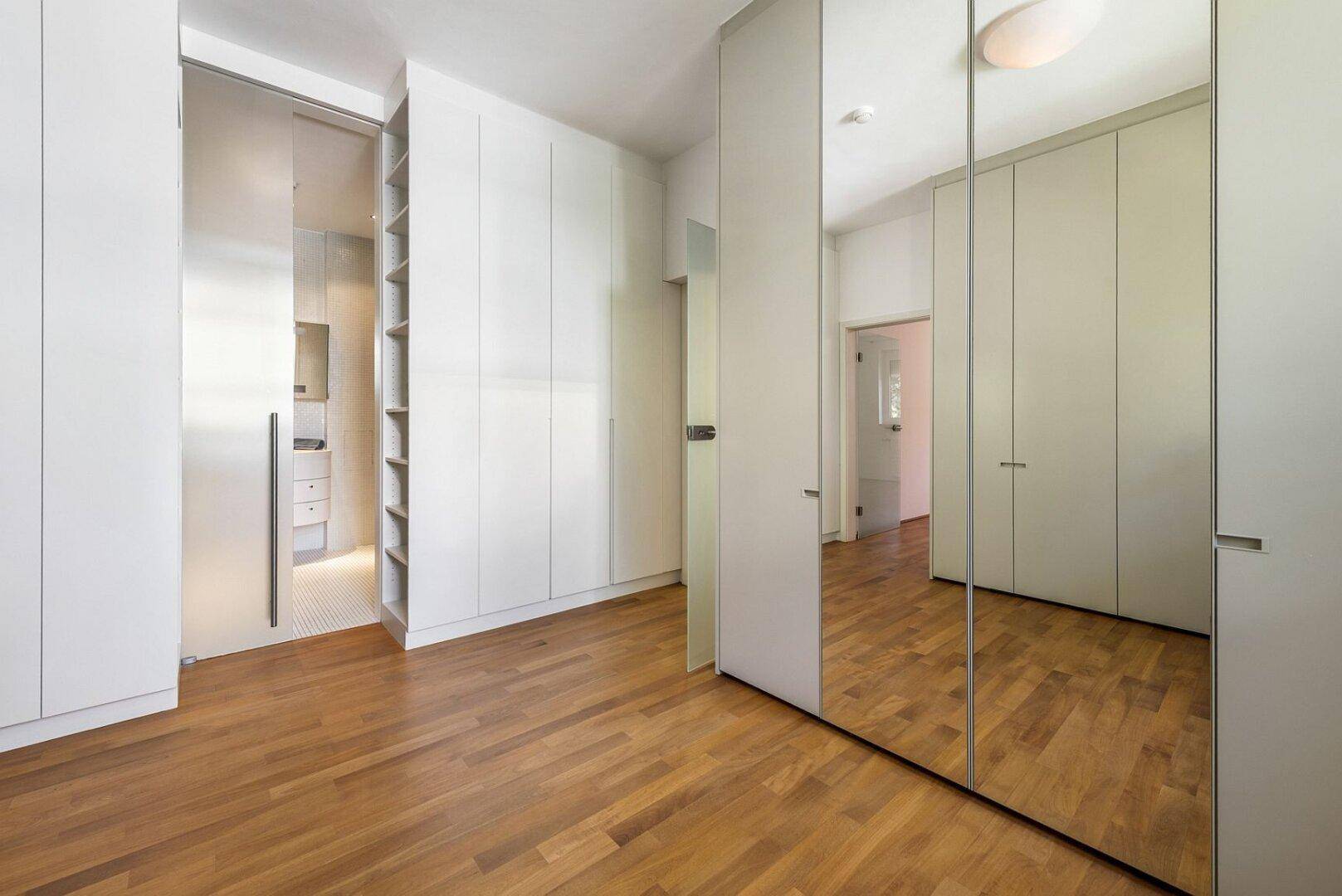 Schlafzimmer mit durchdachten Einbauschränken und Spiegelfronten, die viel Stauraum bieten.