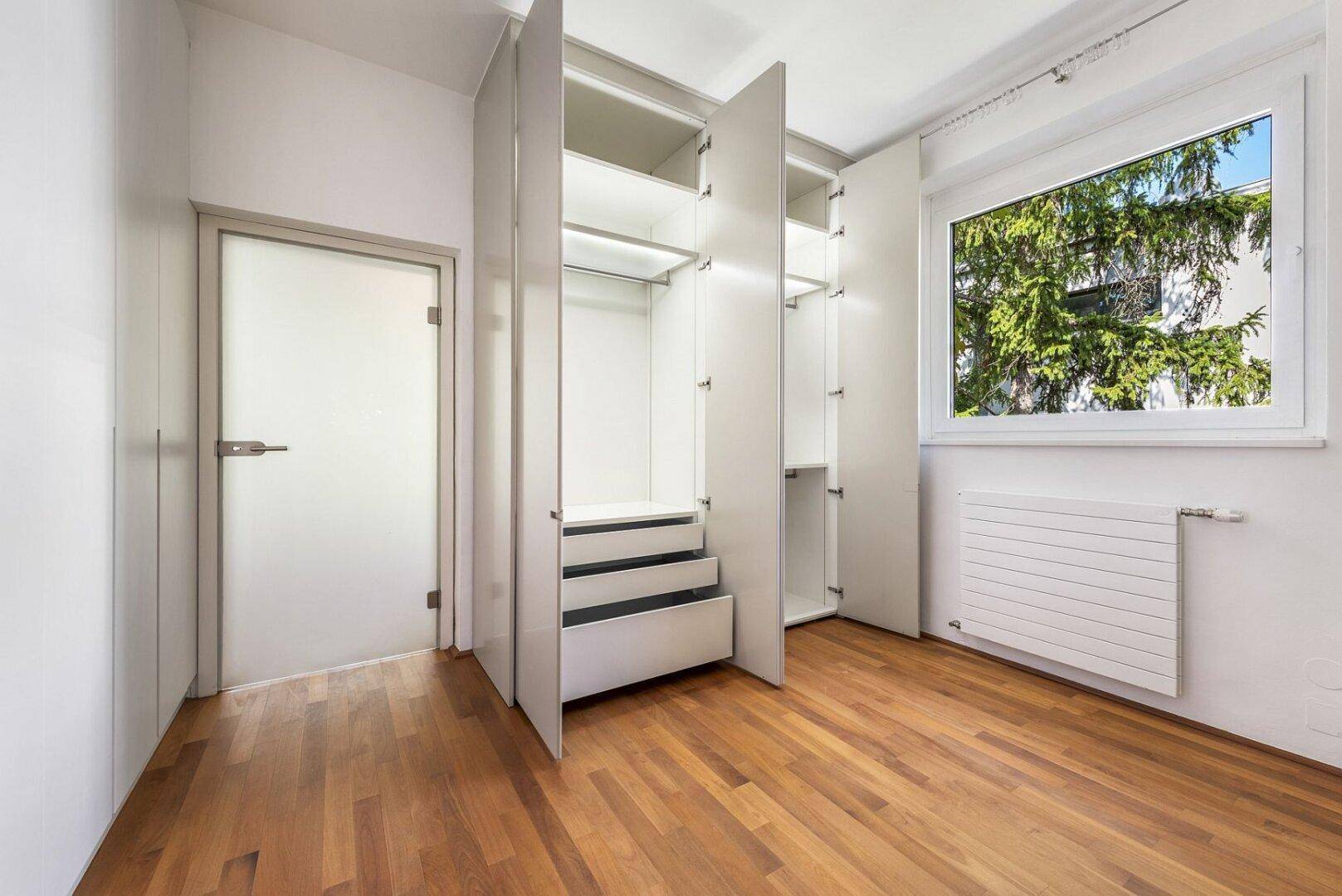 Helles Schlafzimmer mit offenen Einbauschränken und Schubladen, die eine gute Übersicht ermöglichen.