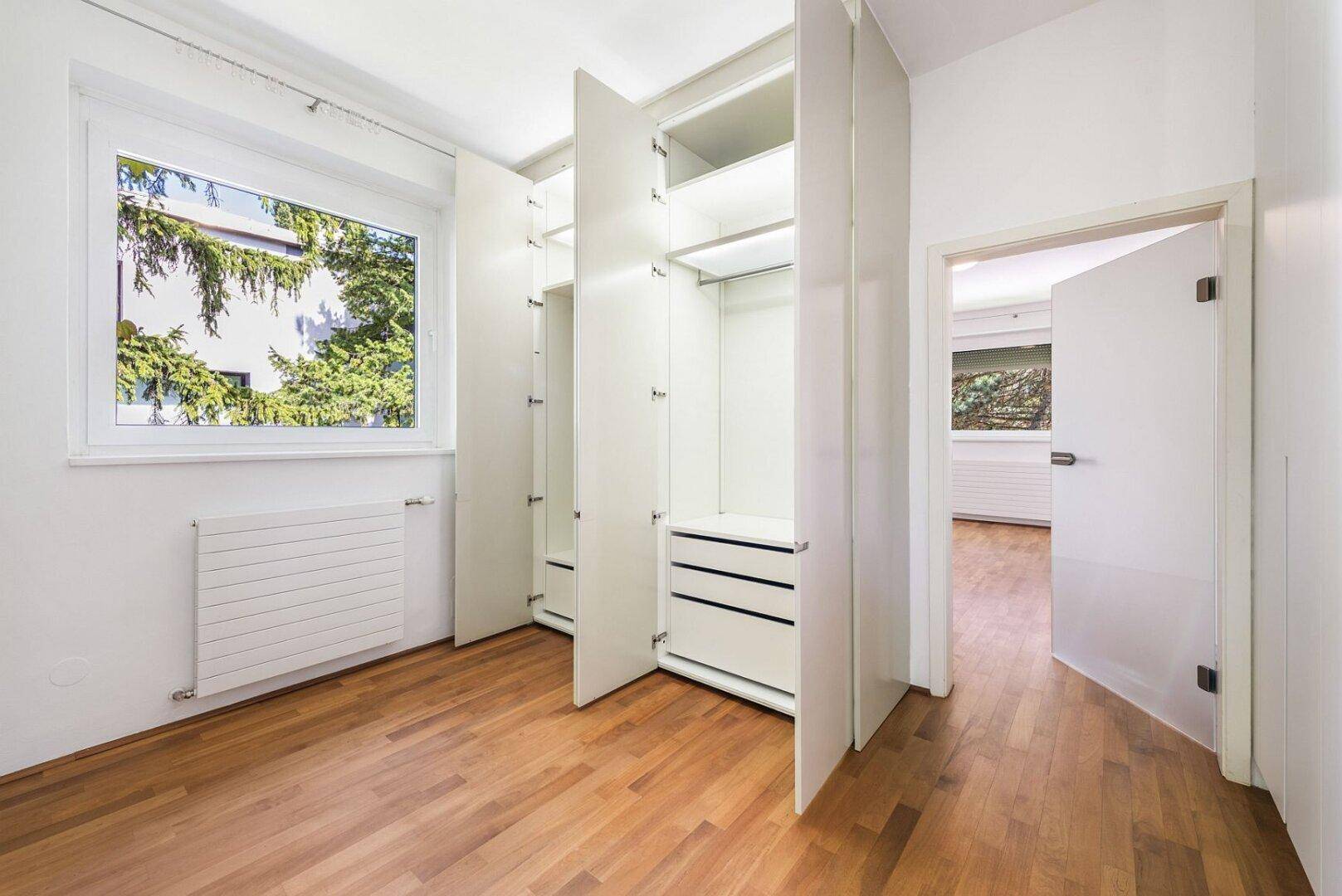 Schlafzimmer mit praktischen Einbauschränken und einem Fenster, das viel Tageslicht hereinlässt.