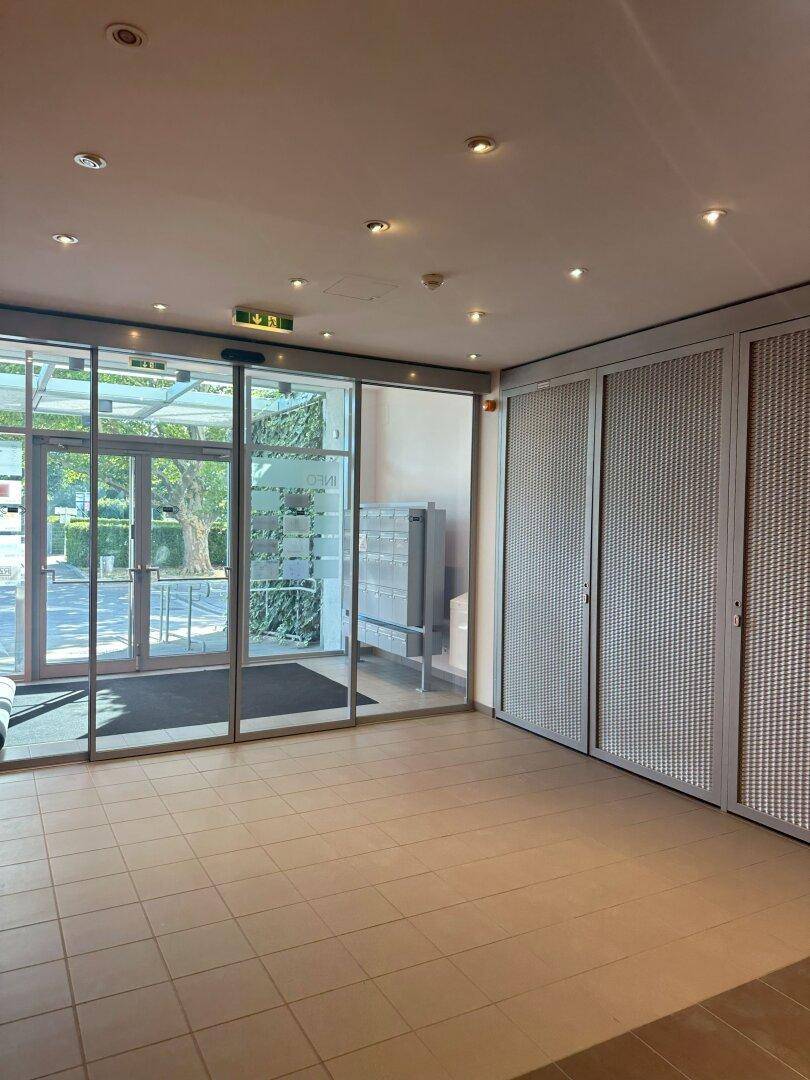 Eingangsbereich des Gebäudes mit Glasfront, Fliesenboden und Briefkästen.