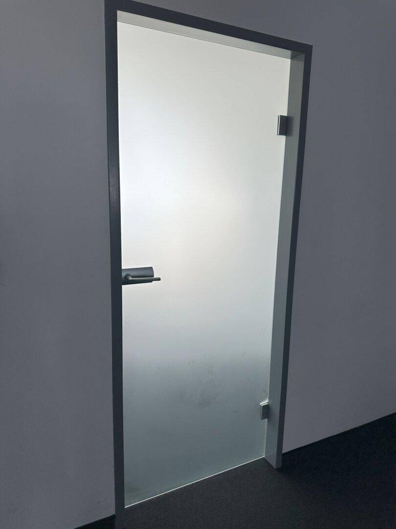 Moderne Glastür mit mattierter Oberfläche in einem Innenbereich, die Licht durchlässt.