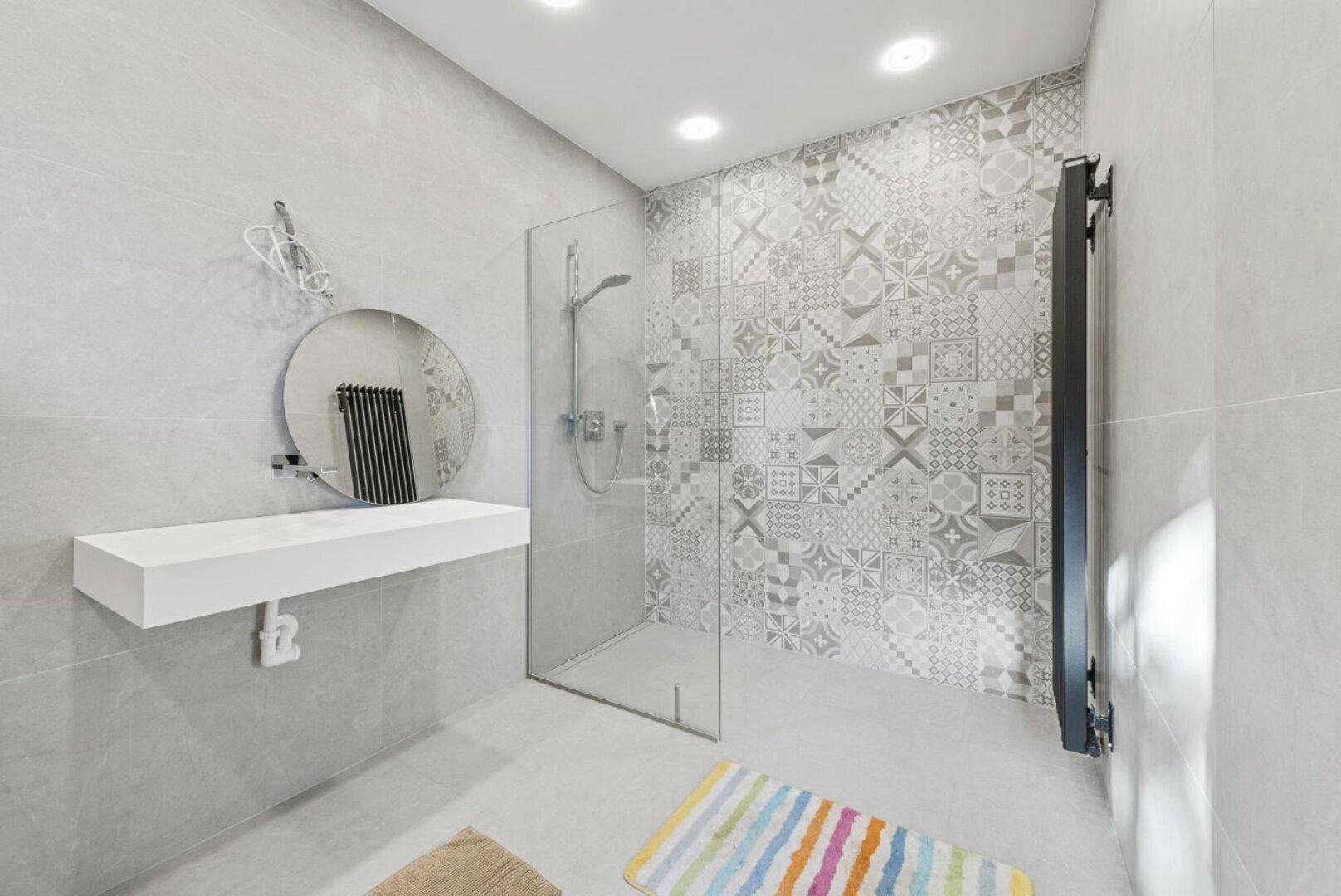 Modernes Badezimmer mit begehbarer Dusche, stilvollem Waschbecken und gemusterten grauen Fliesen.