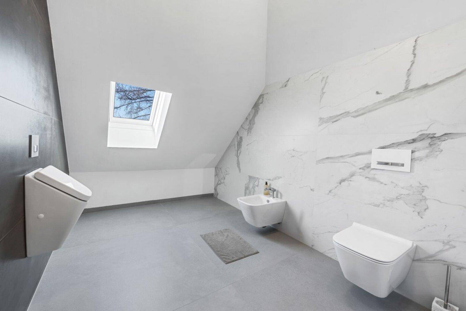 Geräumiges Badezimmer im Dachgeschoss mit Marmorwand, Bidet, WC und Dachfenster für Tageslicht.