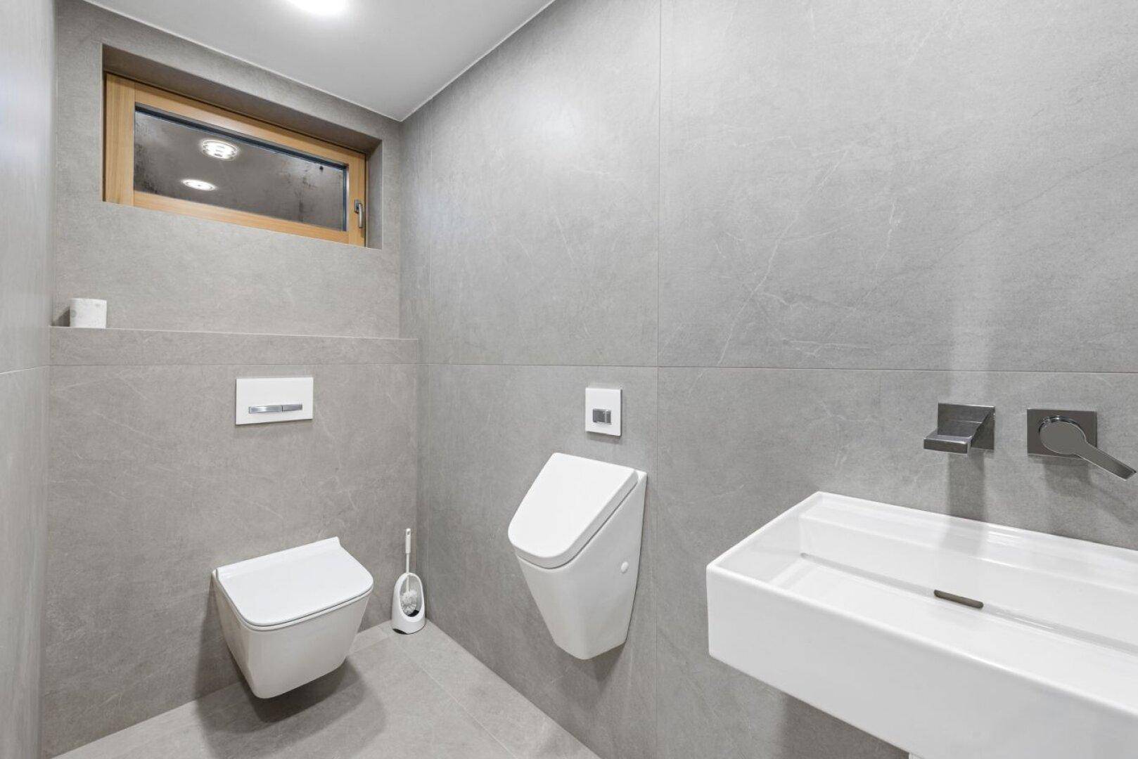 Modernes Gäste-WC mit wandhängendem WC, Urinal, Einzelwaschbecken und Fenster.