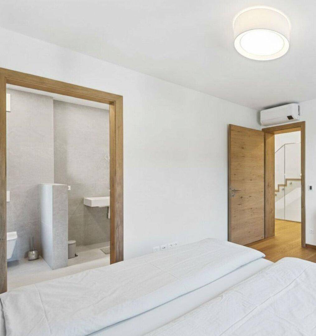Schlafzimmer mit Bett und offenem Zugang zu einem modernen Bad en Suite, ausgestattet mit Klimaanlage.
