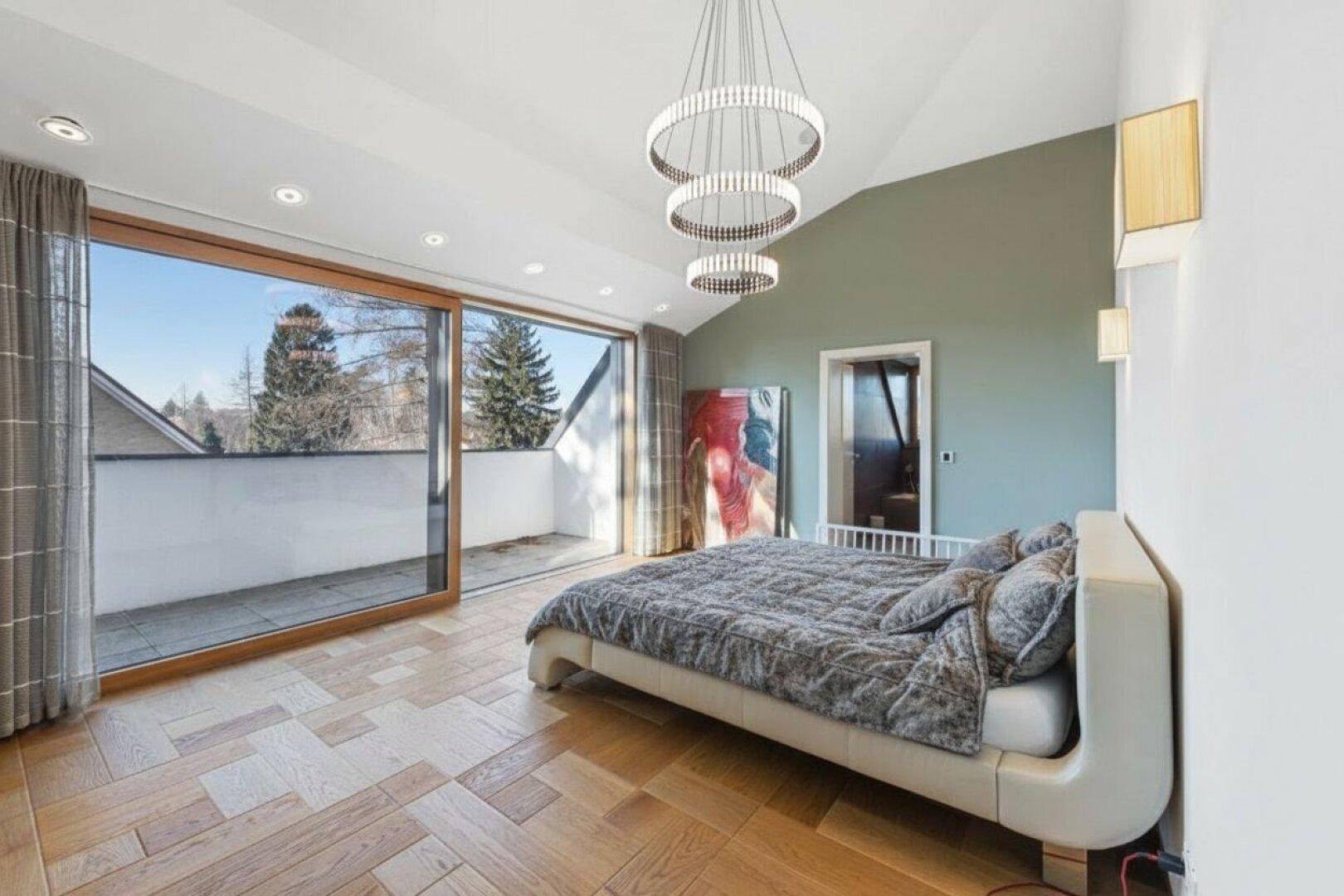 Helles Schlafzimmer mit großem Bett, Dachschräge und direktem Zugang zu einem sonnigen Balkon.