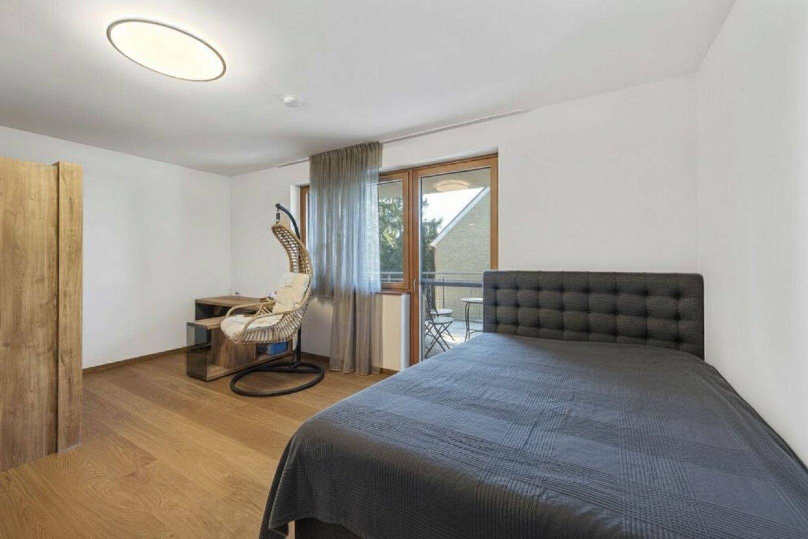 Helles Schlafzimmer mit Einzelbett, Schreibtisch und direktem Zugang zu einem kleinen Balkon.