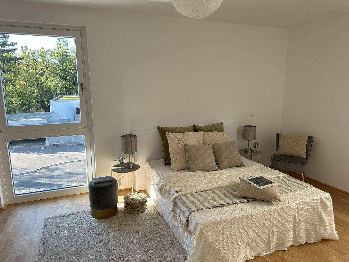 Geräumiges Schlafzimmer mit großem Fenster, Holzboden und viel Tageslicht.