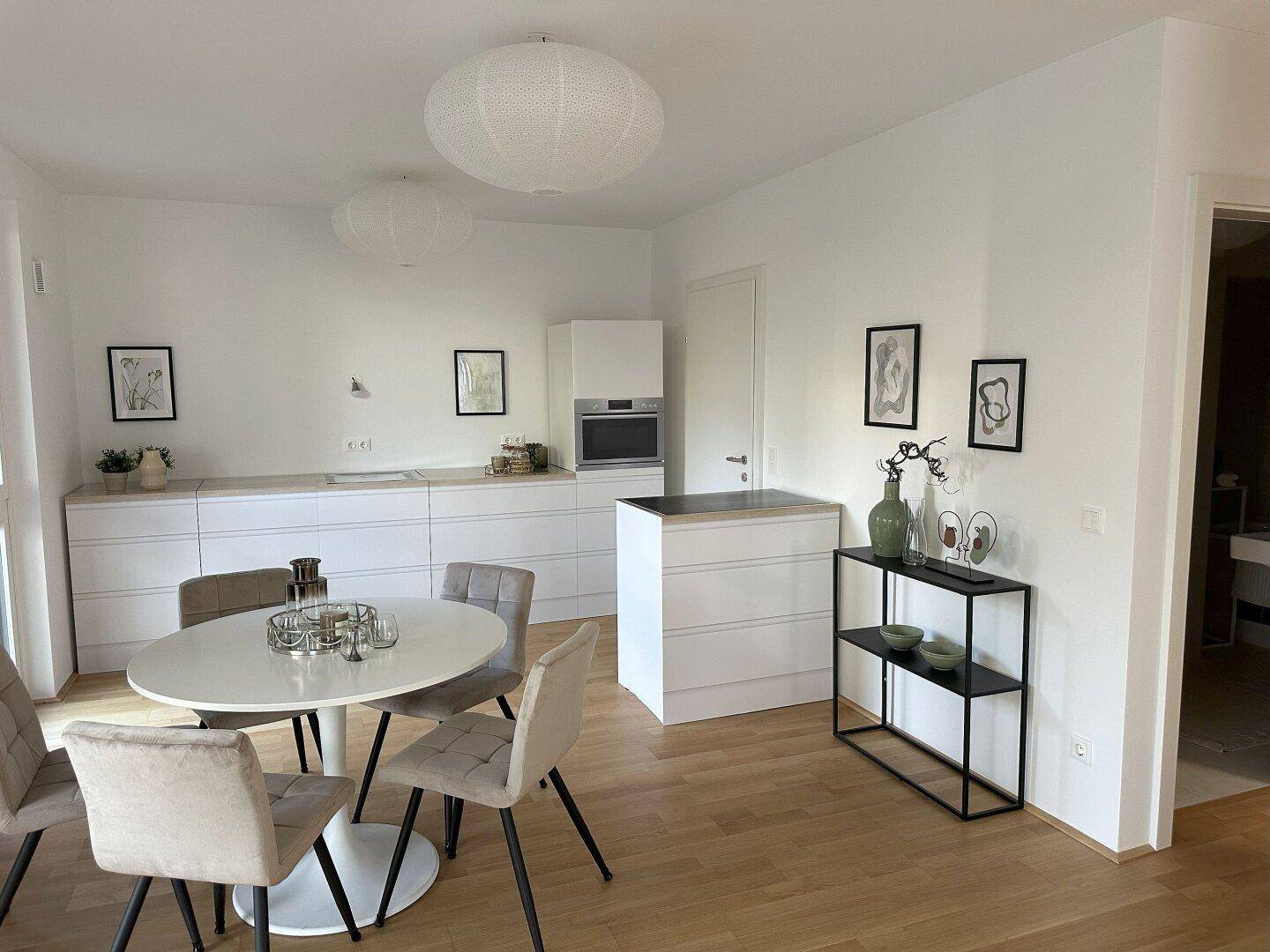 Moderne Küche mit weißer Einbauküche, Esstisch und Holzfußboden.