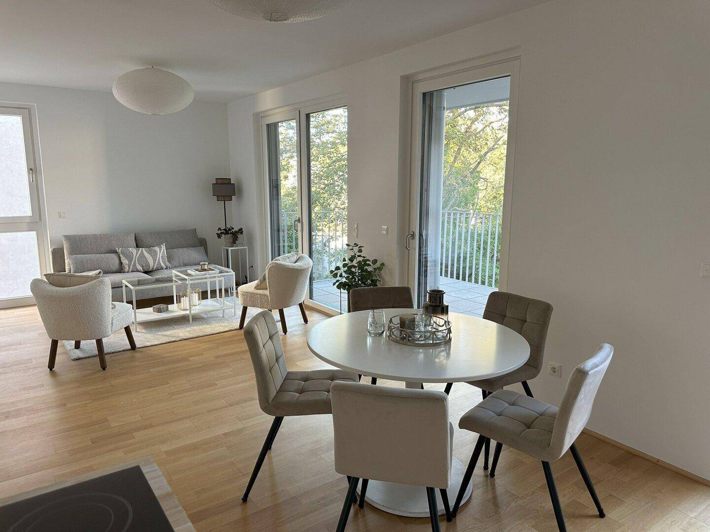 Offener Wohn-Essbereich mit Esstisch, Sofa und Zugang zum Balkon.