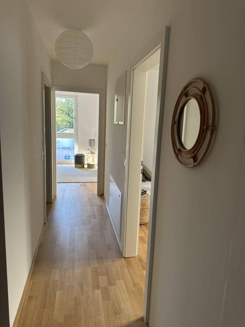 Heller Flur mit Holzboden und Zugang zu weiteren Räumen.