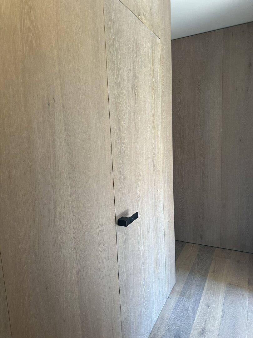 Elegante Holzwandverkleidung mit integrierter Tür und minimalistischem schwarzem Griff.