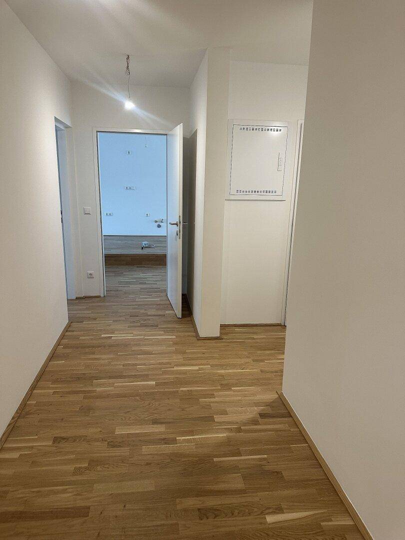 Heller Flur mit Holzboden, der zu verschiedenen Räumen der Wohnung führt.