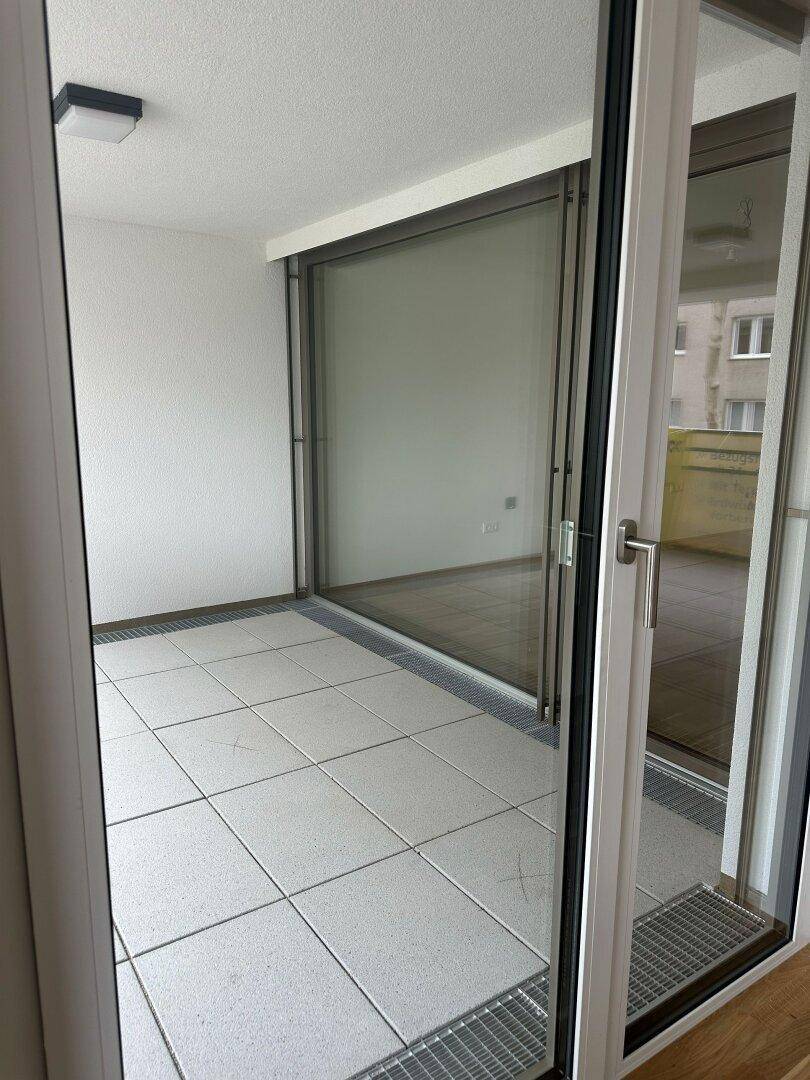 Überdachte Loggia mit Fliesenboden und Blick auf die Umgebung, ideal zum Entspannen.