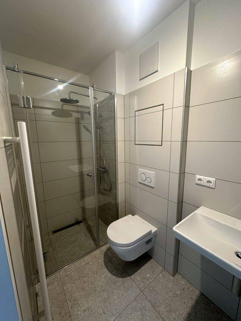 Modernes Badezimmer mit ebenerdiger Dusche, Wand-WC und beheiztem Handtuchhalter.